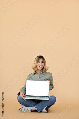 Happy gen z blonde young woman with laptop, smiling student girl holding computer on lap showing white mockup screen advertising elearning online website sitting isolated on background, vertical.