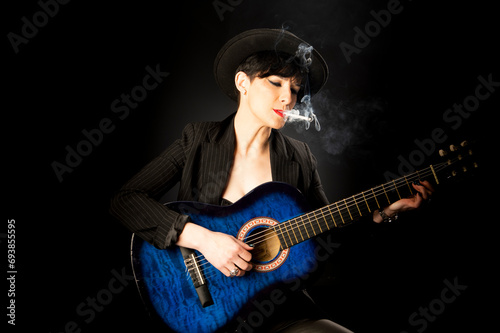 Young beautiful woman in black with a cigarette and an acoustic blue guitar