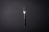 Kitchen fork made of steel on a dark textured background