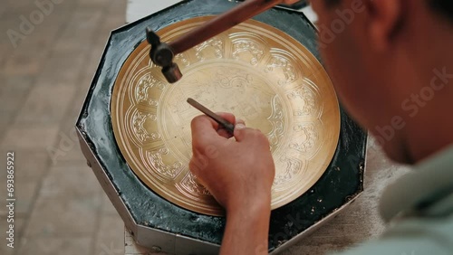 Master, tinsmith, creates a pattern on a brass dish or tray. Close-up. Copper master, hands detail of craftsman at work. Uzbekistan, Bukhara.