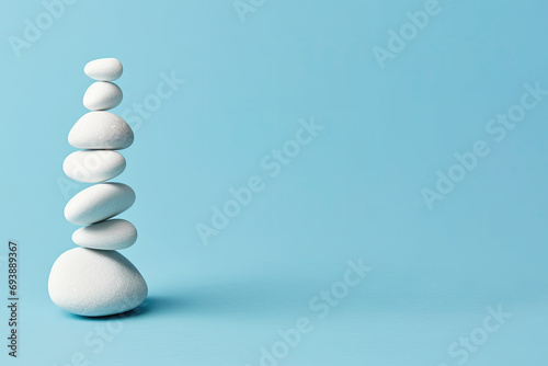  White sea pebble stone stack on light blue background. stack of zen stones on blue . copy space for text photo