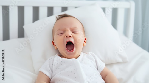 Newborn baby yawns while lying in bed