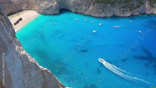Panoramic view of rocky Navagio Beach or Shipwreck Beach. Ships floating turquoise Ionian Sea. Tourists relaxing, sunbathing on sand and enjoying amazing nature of lagoon on Zakynthos island, Greece photo