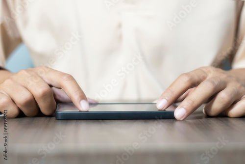 Close-up of a man's hand using a cell phone to search for information. On old wooden table, shopping or business planning concept on touchphone, male businessman using wireless device