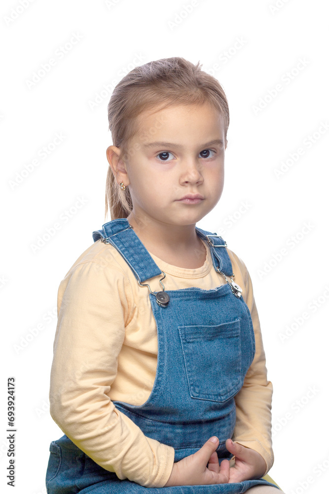 A small child, a 6-7-year-old girl, dressed in a denim dress, on a white background of isolate A small child, a 6-7-year-old girl, dressed in a denim dress, on a white background of isolate