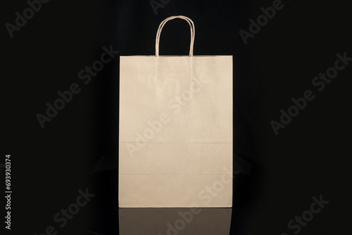 Recyclable craft paper bag for purchases, gifts and takeaway food mock up on black background. Environmentally friendly than single-use plastic bags