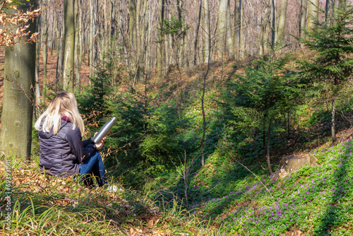 A woman with blonde hair admires the early spring forest