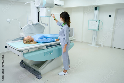 Qualified radiologic technologist preparing woman for radiography photo