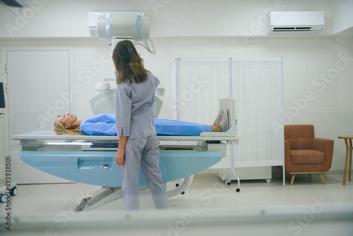 Qualified female radiographer is preparing patient for diagnostic radiography