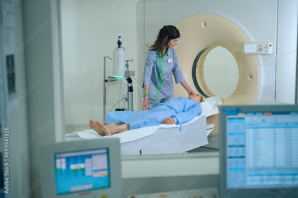 Naklejka premium Experienced radiologic technologist is preparing client for computed tomography
