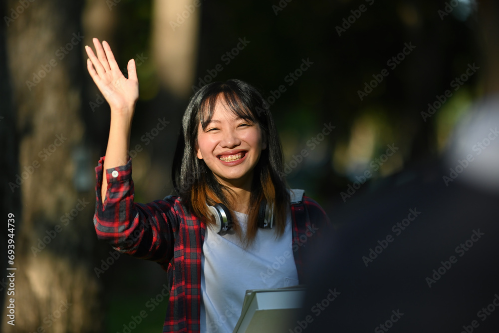Focus on a Young Asian female student greeting her friend, Life in the university concept Focus on a Young Asian female student greeting her friend, Life in the university concept