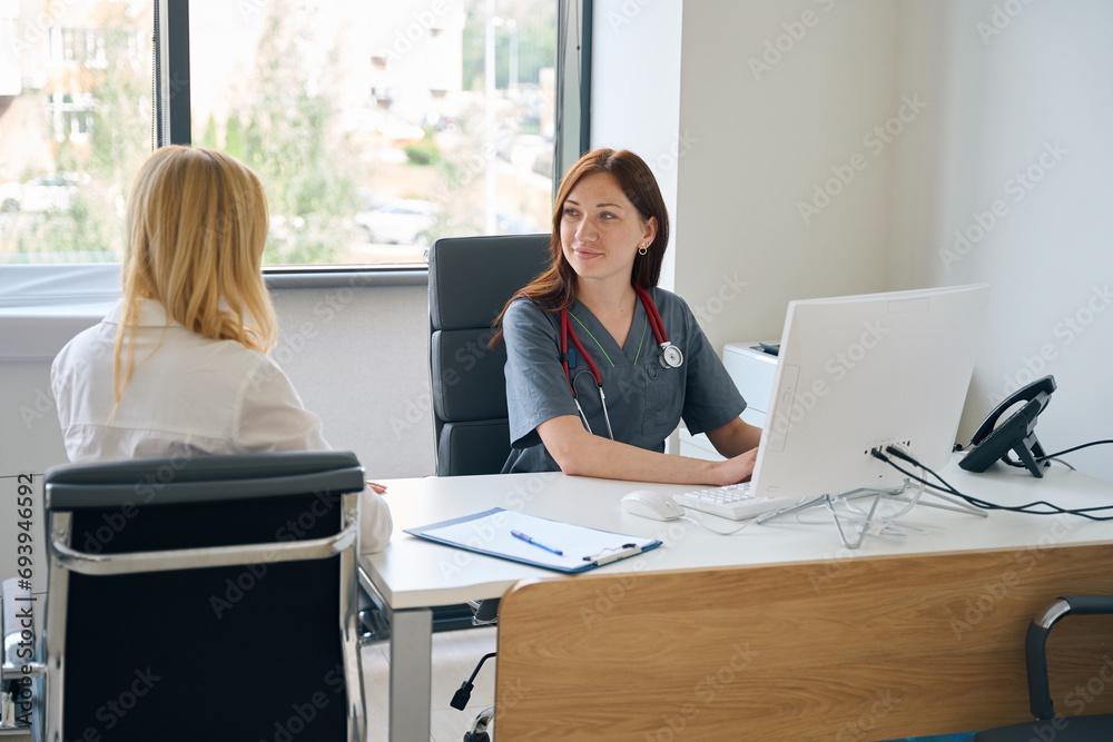 Obraz premium Doctor entering patient data into electronic health record during consultation
