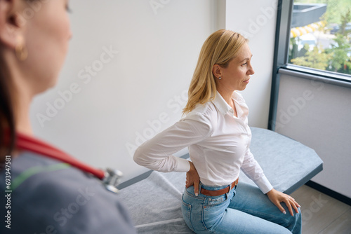 Canvas Print Mature woman complaining of lumbago to physician during medical consultation