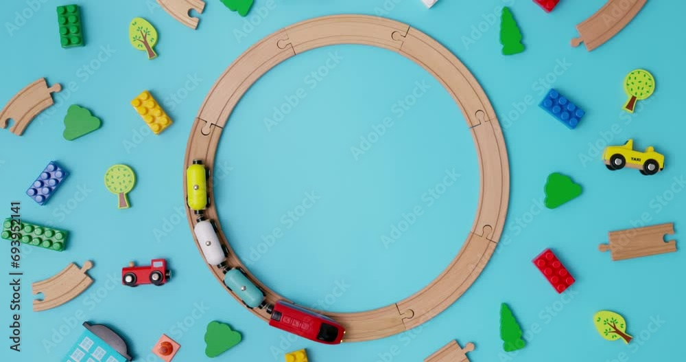 Toy wooden train with cars rides on round railroad on blue background