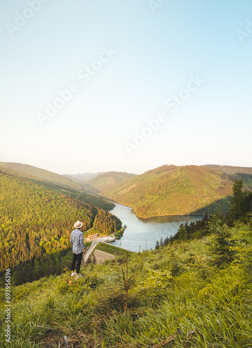 Man in shirt and hat watching sunset illuminating Sance dam, Ostravice, Beskydy mountains, Czech Republic. Enchanting nature of central Europe