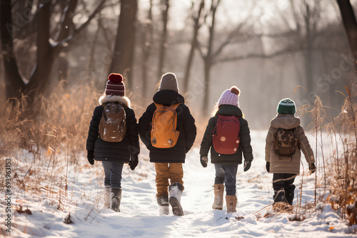 Group of kids walking outside on the snow. Winter park covered in snow. Hiking with kids during winter. Homeschool concept, homeschooling outdoors or nature school, nature schooling. photo