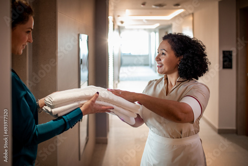 Happy hotel maid giving fresh towels to guest photo