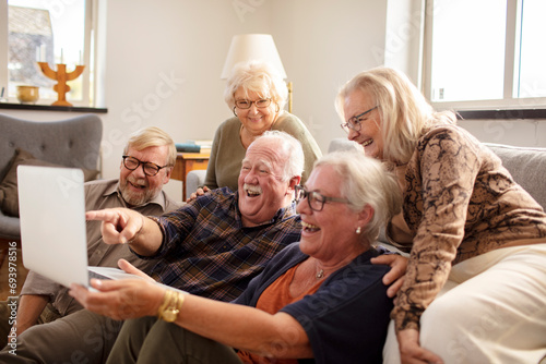 Group of senior people laughing at laptop from home photo