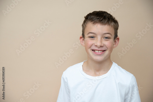 cool 11 years old boy with white t-shirt in front of brown background in the studio