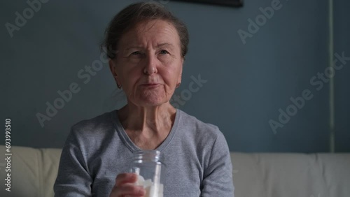 An elderly woman puts a piece of sugar in her mouth and eats it photo