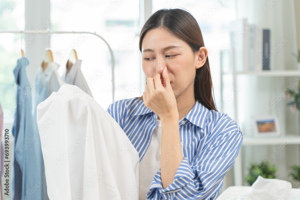 housewife smelling bad odor from damp clothes during laundry. housewife smelling bad odor from damp clothes during laundry.