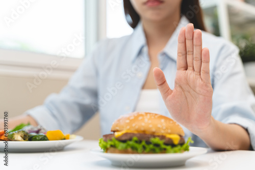 Woman on dieting for good health concept. Woman doing cross arms sign to refuse junk food or fast food hamburger that have many fat. photo