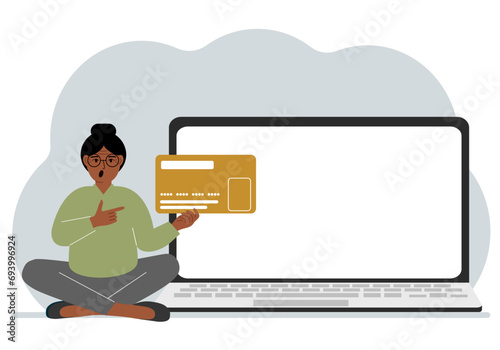 A woman sits cross-legged and holds a large plastic card. Next to the woman is a large laptop with space for text.