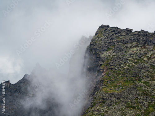 Dramatic fog among giant rocky mountains. Ghostly atmospheric vi