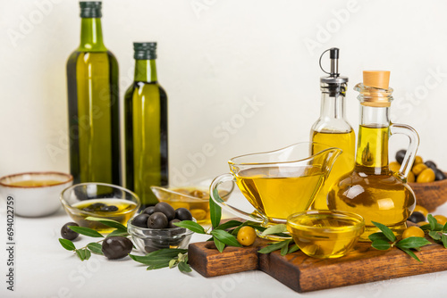Olive oil in a bottle on a white texture background. Oil bottle with branches and fruits of olives. Place for text. copy space. cooking oil and salad dressing.