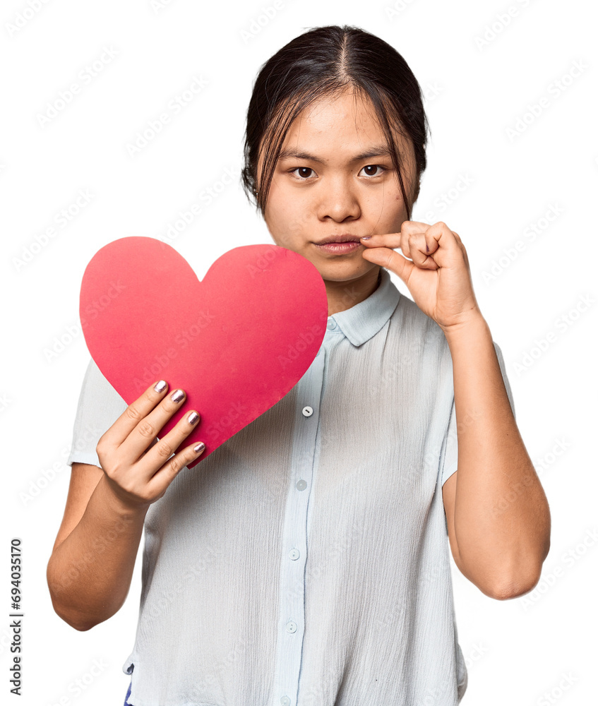 Chinese woman with red Valentine's heart with fingers on lips keeping a secret. Chinese woman with red Valentine's heart with fingers on lips keeping a secret.