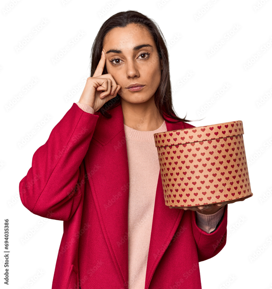Caucasian woman with Valentine's gift box pointing temple with finger, thinking, focused on a task. Caucasian woman with Valentine's gift box pointing temple with finger, thinking, focused on a task.