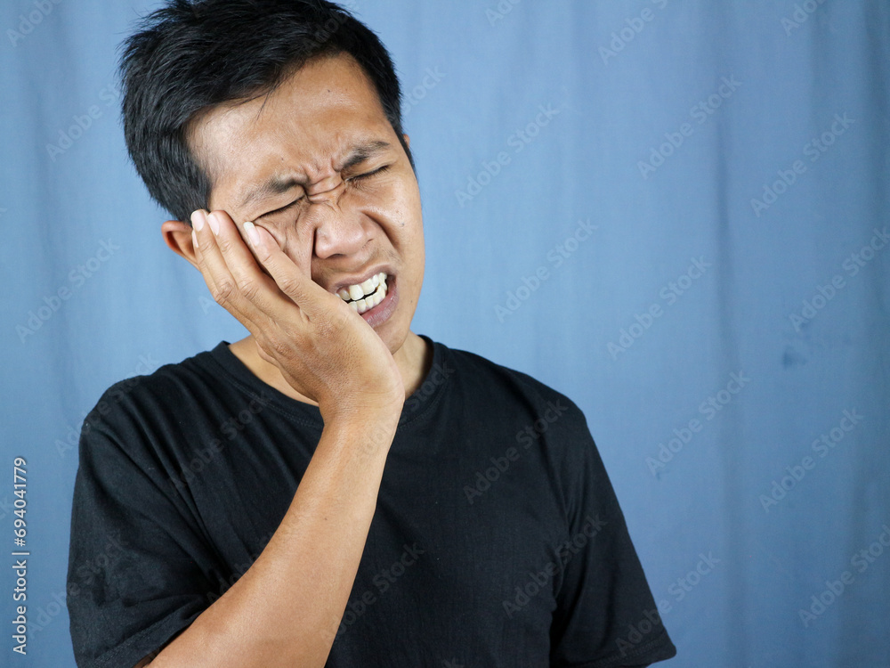 Pain expression of young asian man holding cheek because of toothache. toothache concept Pain expression of young asian man holding cheek because of toothache. toothache concept
