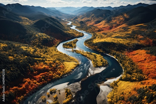 Amidst the vibrant colors of autumn, a braided river flows through a majestic valley surrounded by towering mountains, showcasing the beauty and power of nature's water resources photo