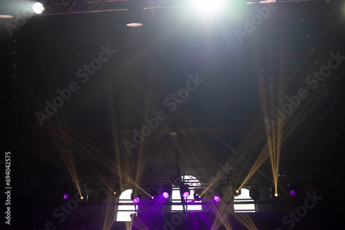 concert stage. bright colorful lighting beams on dark background © alipko
