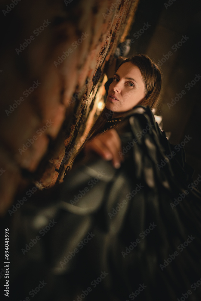 Beautiful girl an angel with the black wings posing in the smoke in the dungeon on dark background. Angel of the night concept. Beautiful girl an angel with the black wings posing in the smoke in the dungeon on dark background. Angel of the night concept.