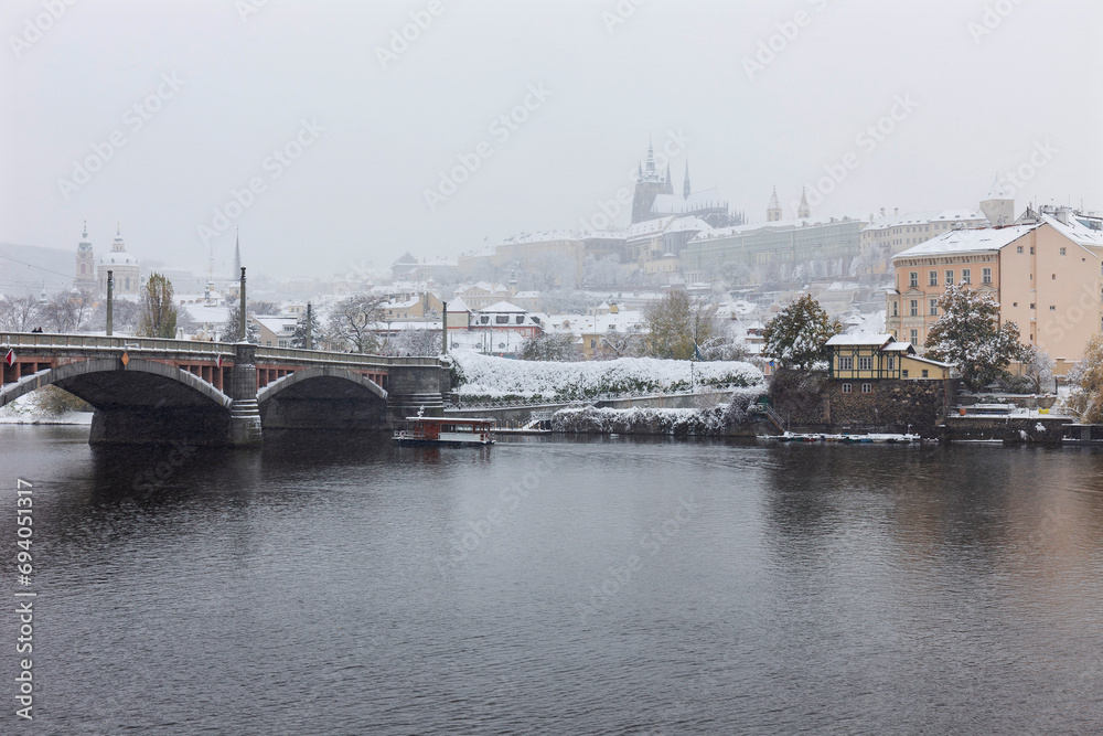 Snowy foggy Prague Lesser Town with gothic Castle above River Vltava, it's snowing, Czech republic