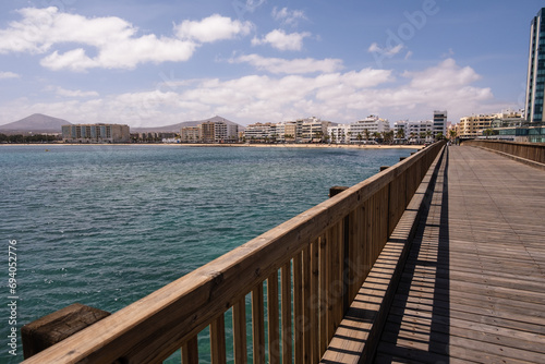 View of the city of Arrecife from the Fermina islet, from a wooden bridge. Turquoise blue water. Sky with big white clouds. Seascape. Lanzarote, Canary Islands, Spain. © Jess