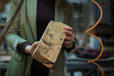 A craftsperson examines a uniquely textured piece of burl wood, appreciating its complex patterns and potential for a woodworking project.