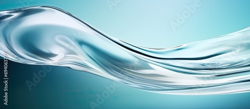 Transparent liquid moisturizer flowing on a turquoise surface.
