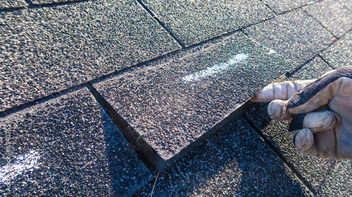 Residential roof inspection for an insurance claim due to storm damage. The asphalt shingles show signs of damage. 