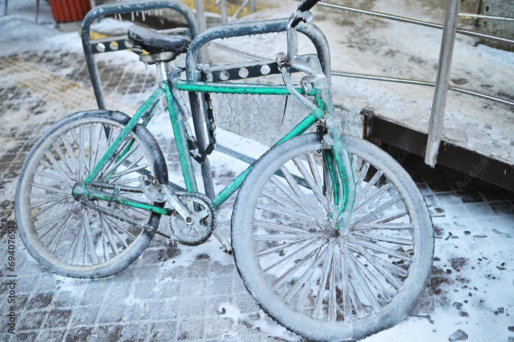 green retro bike in ice on a background of snow in winter in a severe frost.