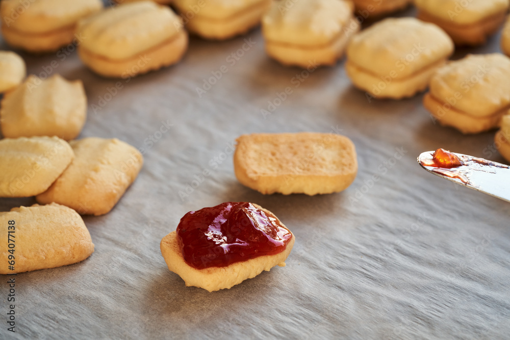 Filling traditional Christmas cookies with strawberry jam - preparation of homemade pastry