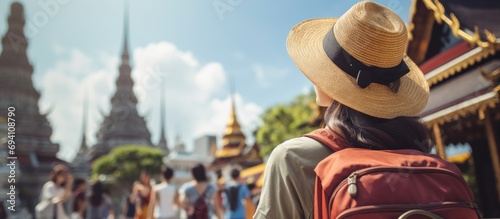 Asian woman backpacker taking selfies and pictures in the city. A young girl traveler recording vlogs on her holiday trip to a Buddha temple in Thailand.