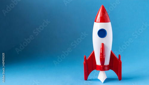 A red and white toy rocket on a blue background