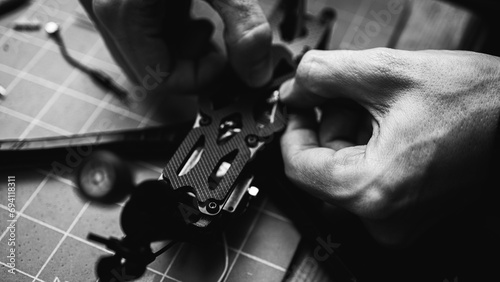 black and white photo, Frame, FPV racing drone frame, assembly, soldering, for the armed forces of Ukraine, installed with tools on the desktop, close-up view