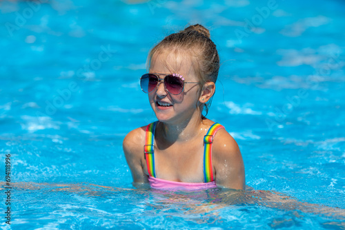 Child in swimming pool. Tropical vacation for family with kids. Little girl wearing swimsuit playing in outdoor pool of exotic island resort. Water and swim fun for children