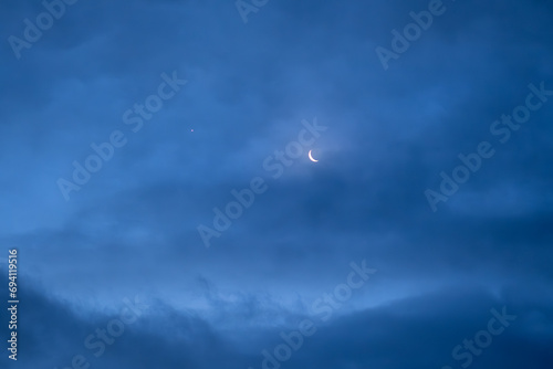 Night sky with old thin bright Moon and star Venus in the clouds, can be used as background. photo