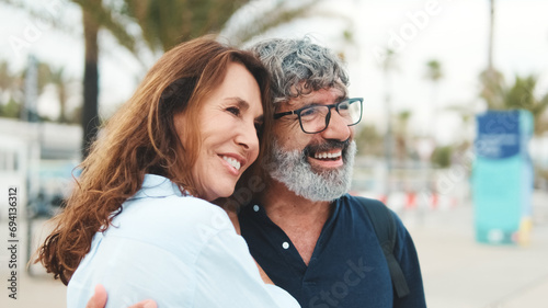 Close-up of an elderly couple standing on the embankment and looking into the distance with smile