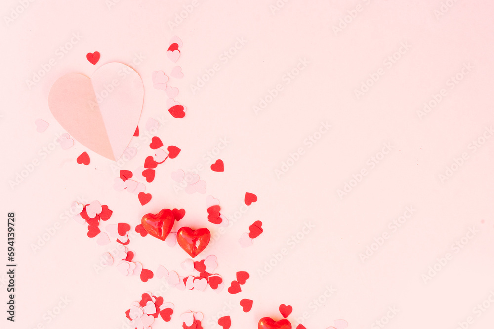 Valentines day festive background with scattred pink and red hearts over pink background with copy space