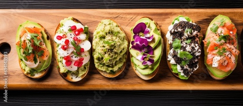 Seafood and caviar bruschetta with avocado, cheese, and radish on a wooden board, viewed from above.